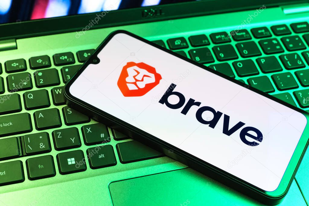 Prague, Czechia - 09 02 2025: Phone on laptop keyboard lit by colored light shows Brave logo. Brave is a web browser focused on privacy and speed.