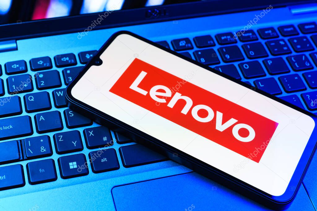 Prague, Czechia - 09 02 2025: Phone on laptop keyboard lit by colored light shows Lenovo logo. Lenovo is a technology company producing computers and electronics.