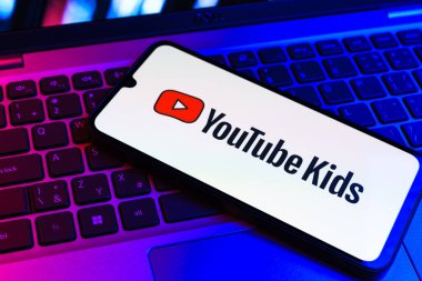 Prag, Çek Cumhuriyeti - 09 02 2025: Renkli ışık tarafından yakılan dizüstü bilgisayardaki telefon Youtube Kids logosunu gösteriyor. Youtube Kids çocuk dostu video içeriği için bir platformdur.
