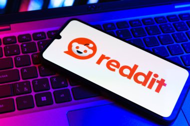 Prag, Çek Cumhuriyeti - 09 02 2025: Renkli ışık tarafından yakılan dizüstü bilgisayardaki telefon Reddit logosunu gösteriyor. Reddit tartışma, haber ve toplum içeriği için bir platformdur.