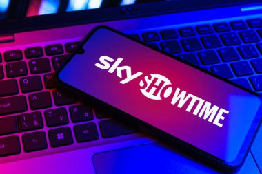 Prag, Çek Cumhuriyeti - 09 02 2025: Renkli ışık tarafından aydınlatılan dizüstü bilgisayardaki telefon SkyShowtime logosunu gösteriyor. SkyShowtime, sinema ve televizyon dizileri için bir yayın platformudur..