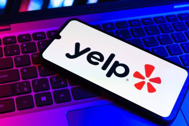 Prag, Çek Cumhuriyeti - 09 02 2025: Renkli ışık tarafından yakılan dizüstü bilgisayardaki telefon Yelp logosunu gösteriyor. Yelp yerel işletmeleri bulmak ve incelemek için bir platformdur.
