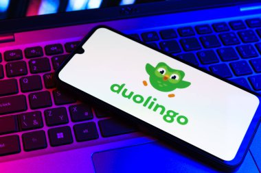 Prag, Çek Cumhuriyeti - 09 02 2025: Diz üstü bilgisayardaki telefon renkli ışık Duolingo logosunu gösteriyor. Duolingo interaktif olarak dil öğrenmek için bir platformdur..