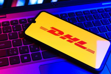 Prag, Çek Cumhuriyeti - 09 02 2025: DHL logosu renkli ışık tarafından yakılan dizüstü bilgisayardaki telefon. DHL uluslararası nakliye hizmeti sunan bir lojistik şirketidir..
