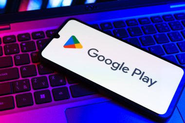 Prag, Çek Cumhuriyeti - 09 02 2025: Google Play logosunun renkli ışıklarla aydınlatıldığı dizüstü bilgisayardaki telefon. Google Play uygulamaları, oyunları ve dijital içeriği indirmek için bir platformdur.