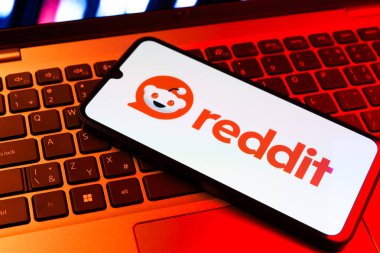 Prag, Çek Cumhuriyeti - 09 02 2025: Renkli ışık tarafından yakılan dizüstü bilgisayardaki telefon Reddit logosunu gösteriyor. Reddit tartışma, haber ve toplum içeriği için bir platformdur.