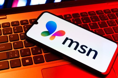 Prag, Çek Cumhuriyeti - 09 02 2025: MSN logosu renkli ışık tarafından yakılan dizüstü bilgisayardaki telefon. MSN haber, e-posta ve çevrimiçi hizmetler için bir platformdur.