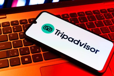 Prag, Çek Cumhuriyeti - 09 02 2025: Renkli ışık tarafından yakılan dizüstü bilgisayardaki telefon TripDanışman logosunu gösteriyor. Seyahat danışmanı seyahat değerlendirmeleri, rezervasyonlar ve tavsiyeler için bir platformdur..