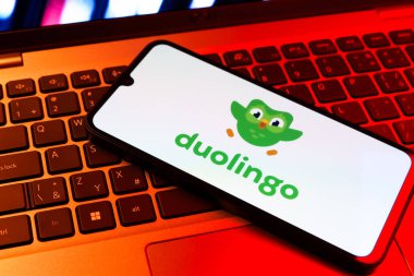 Prag, Çek Cumhuriyeti - 09 02 2025: Diz üstü bilgisayardaki telefon renkli ışık Duolingo logosunu gösteriyor. Duolingo interaktif olarak dil öğrenmek için bir platformdur..
