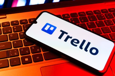 Prag, Çek Cumhuriyeti - 09 02 2025: Renkli ışık tarafından yakılan dizüstü bilgisayardaki telefon Trello logosunu gösteriyor. Trello, tahta ve görevleri kullanarak proje yönetimi için bir platformdur.