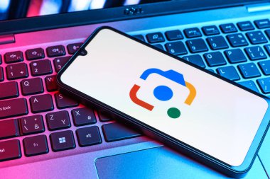 Prag, Çek Cumhuriyeti - 09 02 2025: Laptop klavyesindeki telefon renkli ışıkla aydınlatılmış Google Lens logosunu gösteriyor. Google Lens, resimlerdeki görsel arama ve bilgi için kullanılan bir araçtır..