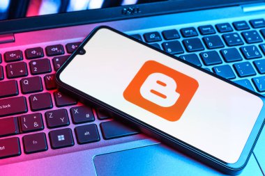 Prag, Çek Cumhuriyeti - 09 02 2025: Renkli ışık tarafından aydınlatılan dizüstü bilgisayardaki telefon blogger logosunu gösteriyor. Blogger blog oluşturma ve yayınlama için bir platformdur.