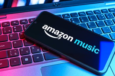 Prag, Çek Cumhuriyeti - 09 02 2025: Renkli ışık tarafından aydınlatılan dizüstü bilgisayardaki telefon Amazon Müzik logosunu gösteriyor. Amazon Müzik müzik müzik için bir platformdur..