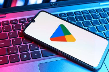 Prag, Çek Cumhuriyeti - 09 02 2025: Google Play logosunun renkli ışıklarla aydınlatıldığı dizüstü bilgisayardaki telefon. Google Play uygulamaları, oyunları ve dijital içeriği indirmek için bir platformdur.