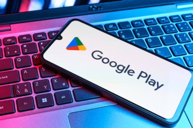 Prag, Çek Cumhuriyeti - 09 02 2025: Google Play logosunun renkli ışıklarla aydınlatıldığı dizüstü bilgisayardaki telefon. Google Play uygulamaları, oyunları ve dijital içeriği indirmek için bir platformdur.