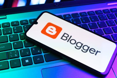 Prag, Çek Cumhuriyeti - 09 02 2025: Renkli ışık tarafından aydınlatılan dizüstü bilgisayardaki telefon blogger logosunu gösteriyor. Blogger blog oluşturma ve yayınlama için bir platformdur.