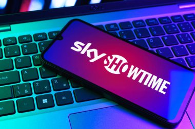 Prag, Çek Cumhuriyeti - 09 02 2025: Renkli ışık tarafından aydınlatılan dizüstü bilgisayardaki telefon SkyShowtime logosunu gösteriyor. SkyShowtime, sinema ve televizyon dizileri için bir yayın platformudur..