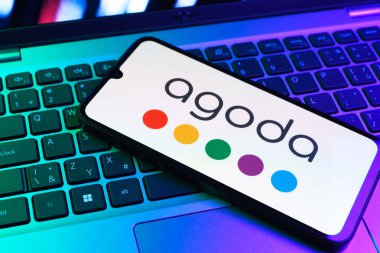 Prag, Çek Cumhuriyeti - 09 02 2025: Telefonun klavyesi renkli ışıklarla aydınlatılmış Agoda logosu gösteriyor. Agoda, otelleri ve seyahat yerlerini ayırtmak için bir platform..