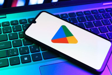 Prag, Çek Cumhuriyeti - 09 02 2025: Google Play logosunun renkli ışıklarla aydınlatıldığı dizüstü bilgisayardaki telefon. Google Play uygulamaları, oyunları ve dijital içeriği indirmek için bir platformdur.