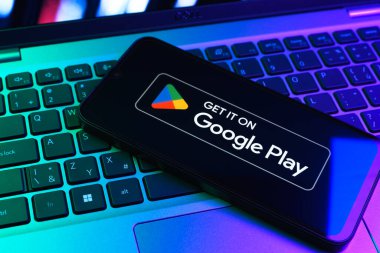 Prag, Çek Cumhuriyeti - 09 02 2025: Google Play logosunun renkli ışıklarla aydınlatıldığı dizüstü bilgisayardaki telefon. Google Play uygulamaları, oyunları ve dijital içeriği indirmek için bir platformdur.