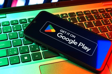 Prag, Çek Cumhuriyeti - 09 02 2025: Google Play logosunun renkli ışıklarla aydınlatıldığı dizüstü bilgisayardaki telefon. Google Play uygulamaları, oyunları ve dijital içeriği indirmek için bir platformdur.