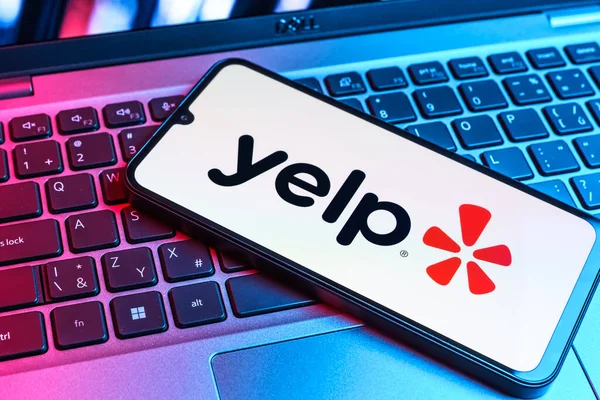 Prag, Çek Cumhuriyeti - 09 02 2025: Renkli ışık tarafından yakılan dizüstü bilgisayardaki telefon Yelp logosunu gösteriyor. Yelp yerel işletmeleri bulmak ve incelemek için bir platformdur.