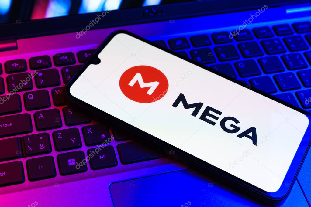 Prague, Czechia - 09 02 2025: Phone on laptop keyboard lit by colored light shows Mega logo. Mega is a platform for cloud storage with encrypted file sharing.