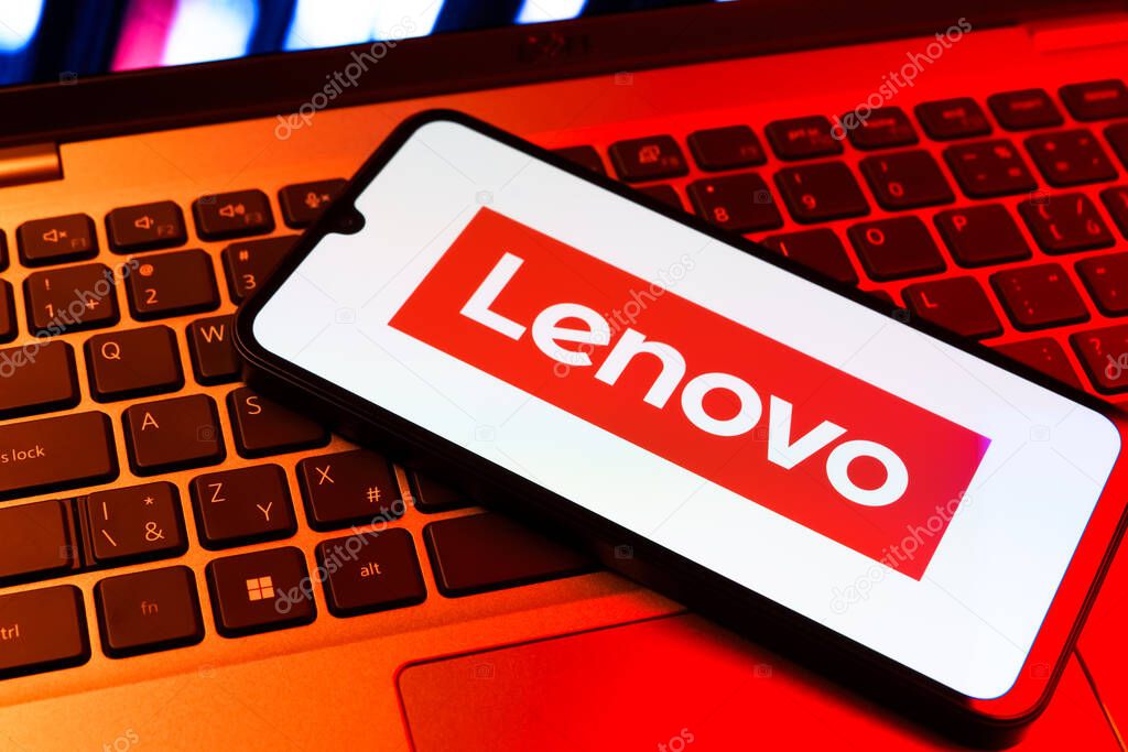 Prague, Czechia - 09 02 2025: Phone on laptop keyboard lit by colored light shows Lenovo logo. Lenovo is a technology company producing computers and electronics.