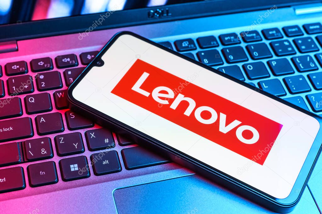 Prague, Czechia - 09 02 2025: Phone on laptop keyboard lit by colored light shows Lenovo logo. Lenovo is a technology company producing computers and electronics.