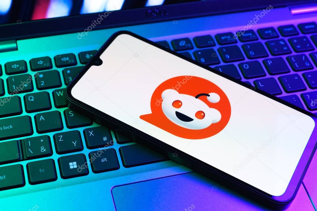 Prague, Czechia - 09 02 2025: Phone on laptop keyboard lit by colored light shows Reddit logo. Reddit is a platform for discussion, news, and community content.