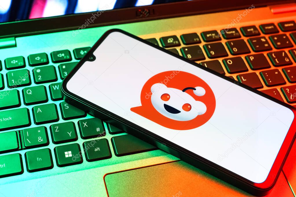 Prague, Czechia - 09 02 2025: Phone on laptop keyboard lit by colored light shows Reddit logo. Reddit is a platform for discussion, news, and community content.