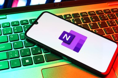 Prag, Çek Cumhuriyeti - 09 02 2025: Laptop klavyesindeki telefon Microsoft OneNote logosunu gösteriyor. Microsoft OneNote not almak ve düzenlemek için bir platformdur.