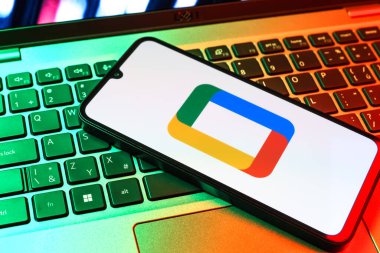 Prag, Çek Cumhuriyeti - 09 02 2025: Laptop klavyesindeki telefon renkli ışık gösterileri Google TV logosunu gösteriyor. Google TV film, program ve uygulamalar için bir platformdur..