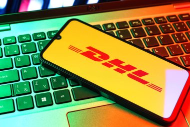 Prag, Çek Cumhuriyeti - 09 02 2025: DHL logosu renkli ışık tarafından yakılan dizüstü bilgisayardaki telefon. DHL uluslararası nakliye hizmeti sunan bir lojistik şirketidir..