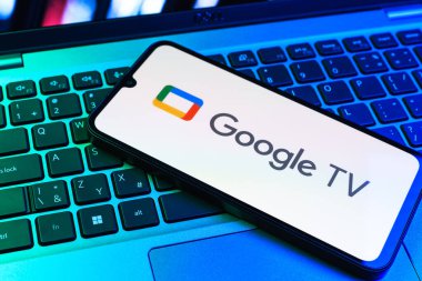 Prag, Çek Cumhuriyeti - 09 02 2025: Laptop klavyesindeki telefon renkli ışık gösterileri Google TV logosunu gösteriyor. Google TV film, program ve uygulamalar için bir platformdur..