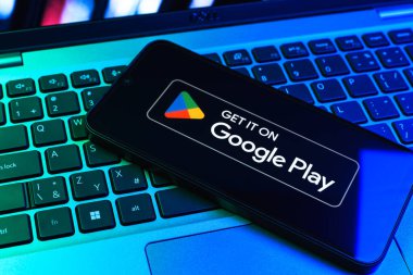 Prag, Çek Cumhuriyeti - 09 02 2025: Google Play logosunun renkli ışıklarla aydınlatıldığı dizüstü bilgisayardaki telefon. Google Play uygulamaları, oyunları ve dijital içeriği indirmek için bir platformdur.