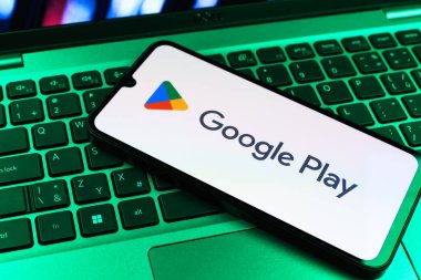 Prag, Çek Cumhuriyeti - 09 02 2025: Google Play logosunun renkli ışıklarla aydınlatıldığı dizüstü bilgisayardaki telefon. Google Play uygulamaları, oyunları ve dijital içeriği indirmek için bir platformdur.