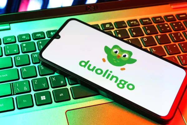Prag, Çek Cumhuriyeti - 09 02 2025: Diz üstü bilgisayardaki telefon renkli ışık Duolingo logosunu gösteriyor. Duolingo interaktif olarak dil öğrenmek için bir platformdur..
