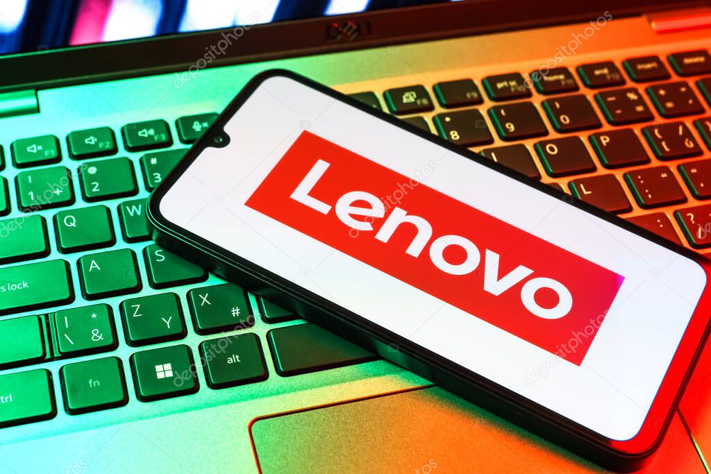 Prague, Czechia - 09 02 2025: Phone on laptop keyboard lit by colored light shows Lenovo logo. Lenovo is a technology company producing computers and electronics.