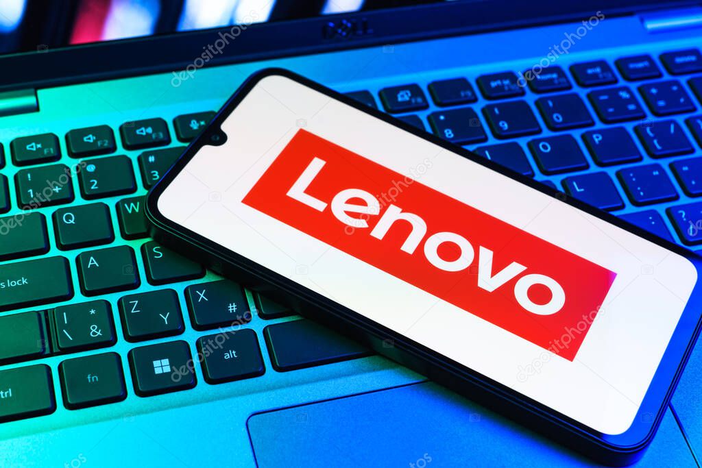 Prague, Czechia - 09 02 2025: Phone on laptop keyboard lit by colored light shows Lenovo logo. Lenovo is a technology company producing computers and electronics.