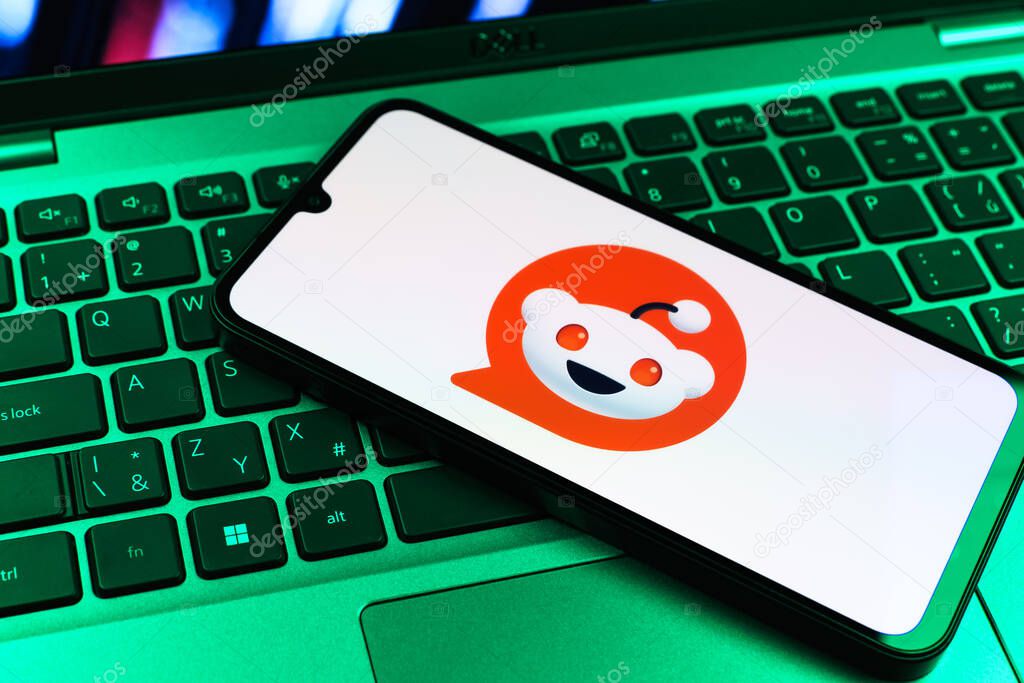 Prague, Czechia - 09 02 2025: Phone on laptop keyboard lit by colored light shows Reddit logo. Reddit is a platform for discussion, news, and community content.