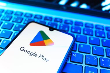 Prag, Çek Cumhuriyeti - 08 19 2025: Google Play logosunu gösteren klavyenin üzerinde duran bir cep telefonunun yakından görüntüsü. Google Play uygulamaları, oyunları ve dijital içeriği indirmek için bir platformdur.