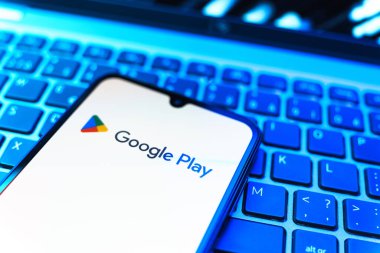 Prag, Çek Cumhuriyeti - 08 19 2025: Google Play logosunu gösteren klavyenin üzerinde duran bir cep telefonunun yakından görüntüsü. Google Play uygulamaları, oyunları ve dijital içeriği indirmek için bir platformdur.