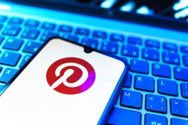 Prag, Çek Cumhuriyeti - 08 19 2025: Pinterest logosunu gösteren klavyenin üzerinde duran cep telefonunun yakından görüntüsü. Pinterest fikirleri görsel olarak keşfetmek ve kaydetmek için bir platformdur..