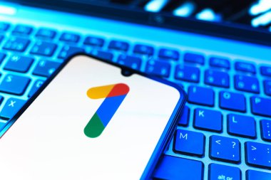 Prag, Çek Cumhuriyeti - 08 19 2025: Bir klavyenin üzerinde duran ve Google One logosunu gösteren cep telefonunun yakından görüntüsü. Google 1 bulut depolama ve abonelik hizmetleri için bir platformdur.
