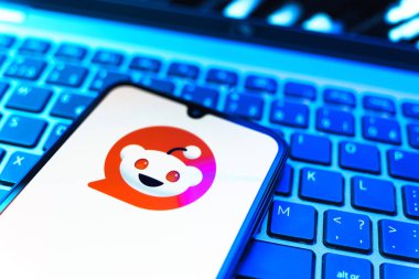 Prag, Çek Cumhuriyeti - 08 19 2025: Bir klavyenin üzerinde duran ve Reddit logosunu gösteren cep telefonunun yakından görüntüsü. Reddit tartışma, haber ve toplum içeriği için bir platformdur.