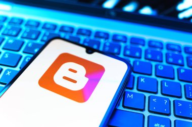 Prag, Çek Cumhuriyeti - 08 19 2025: Klavyenin üzerinde duran ve Blogger logosunu gösteren cep telefonunun yakından görüntüsü. Blogger blog oluşturma ve yayınlama için bir platformdur.