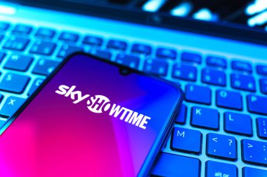 Prag, Çek Cumhuriyeti - 08 19 2025: SkyShowtime logosunu gösteren klavyenin üzerinde duran cep telefonunun yakından görüntüsü. SkyShowtime, sinema ve televizyon dizileri için bir yayın platformudur..