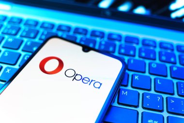 Prag, Çek Cumhuriyeti - 08 19 2025: Opera logosunu gösteren klavyenin üzerinde duran cep telefonunun yakından görüntüsü. Opera hızlı ve güvenli internet taraması için bir web tarayıcısıdır.