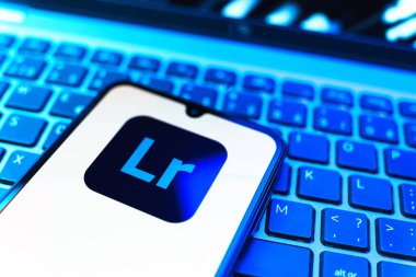 Prag, Çek Cumhuriyeti - 08 19 2025: Klavyede duran ve Lightroom logosunu gösteren cep telefonunun yakından görüntüsü. Lightroom fotoğraf düzenleme ve yönetim için bir yazılımdır..